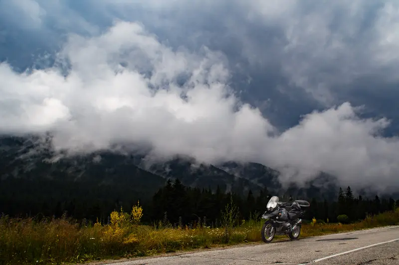 BMW GS on mountain road under storm clouds