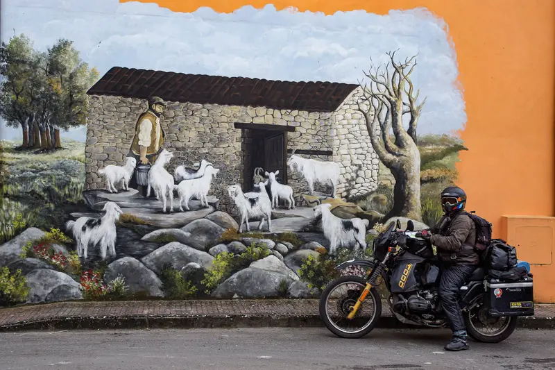 Rider on loaded bike beside painted mural wall