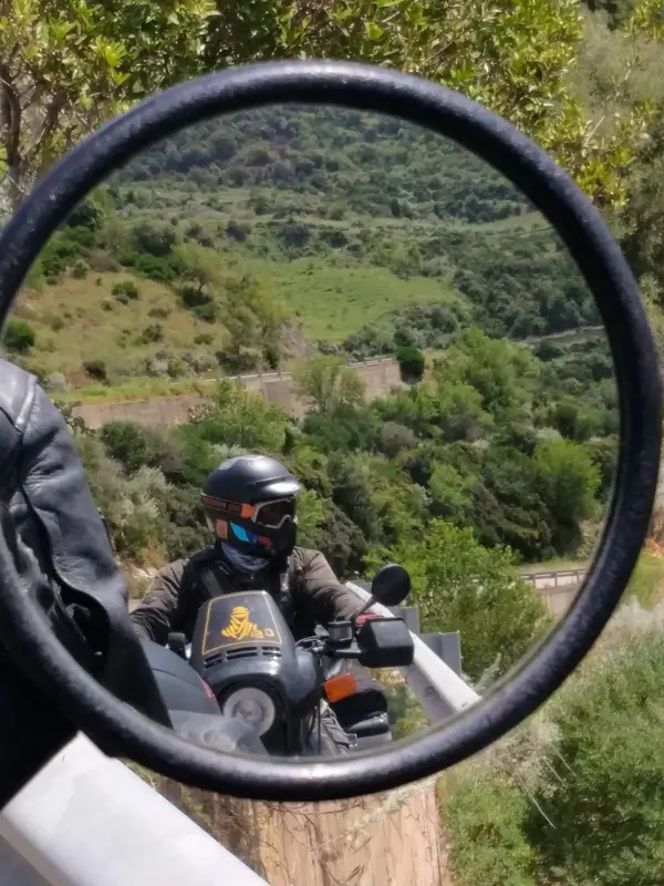 Rider reflected in motorcycle mirror on mountain road